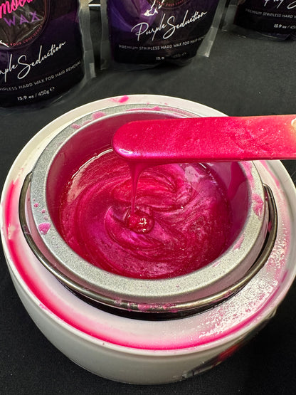 Smooth melted pink hard wax in a professional wax warmer showing the working consistency on a waxing spatula.